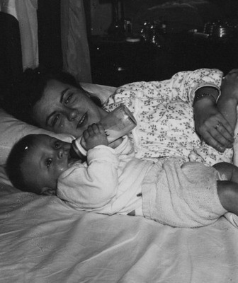 1950s Mother Putting Down Baby Bedtime Feeding Bottle Bedroom Candid Moment