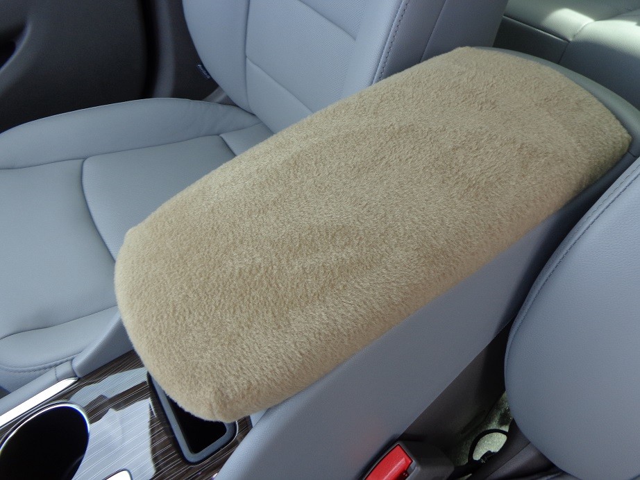 Tan fabric armrest cover with smooth edges, resting on a gray leather car center console.