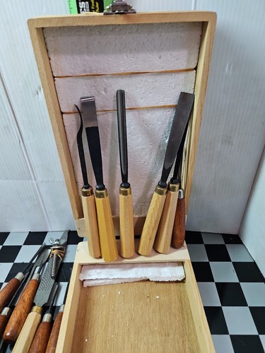 11 chisels with wooden handles in foam-lined wooden box, including a few sharpening stone tools.