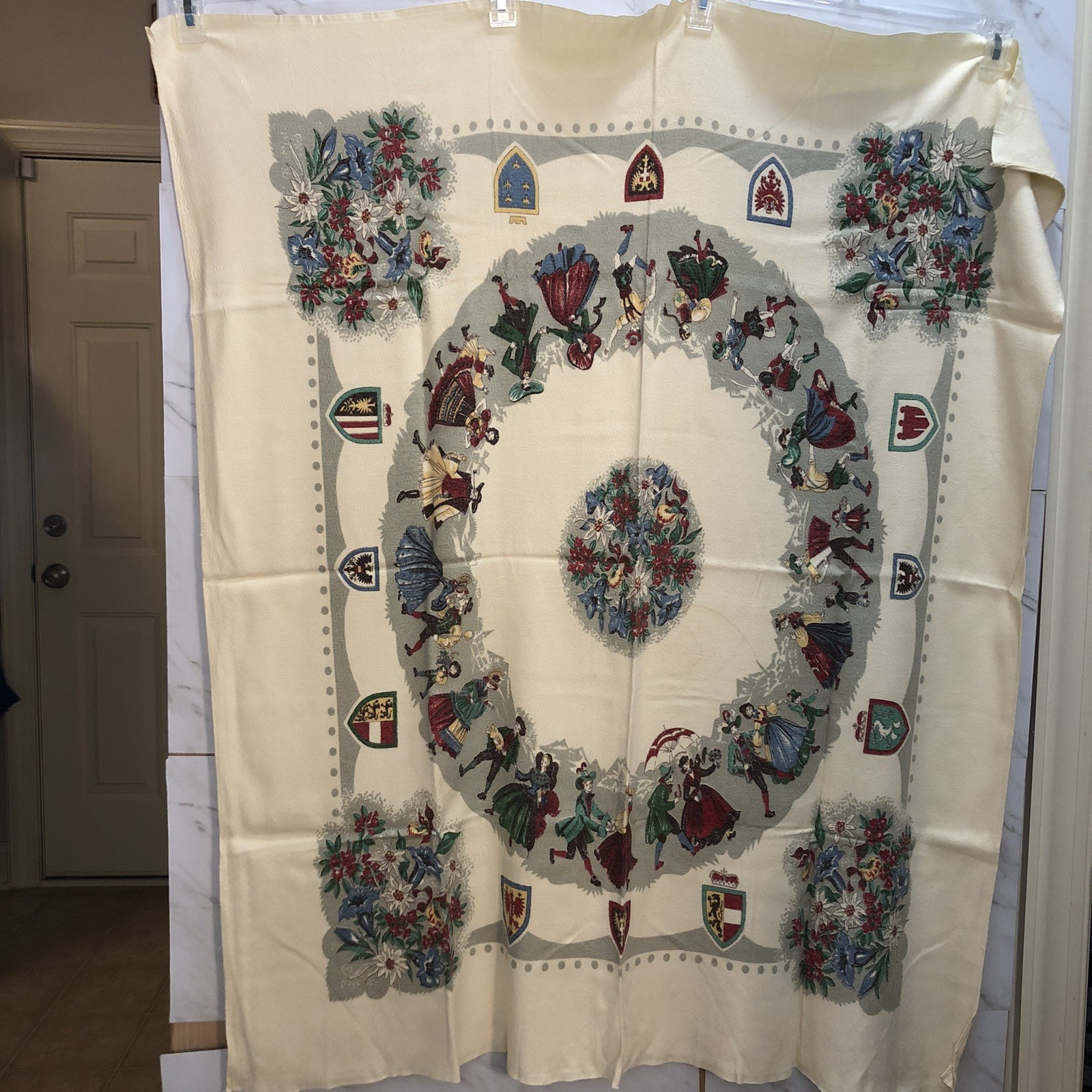 Cream linen tablecloth printed with a ring of dancing Bavarian couples and a floral center medallion.