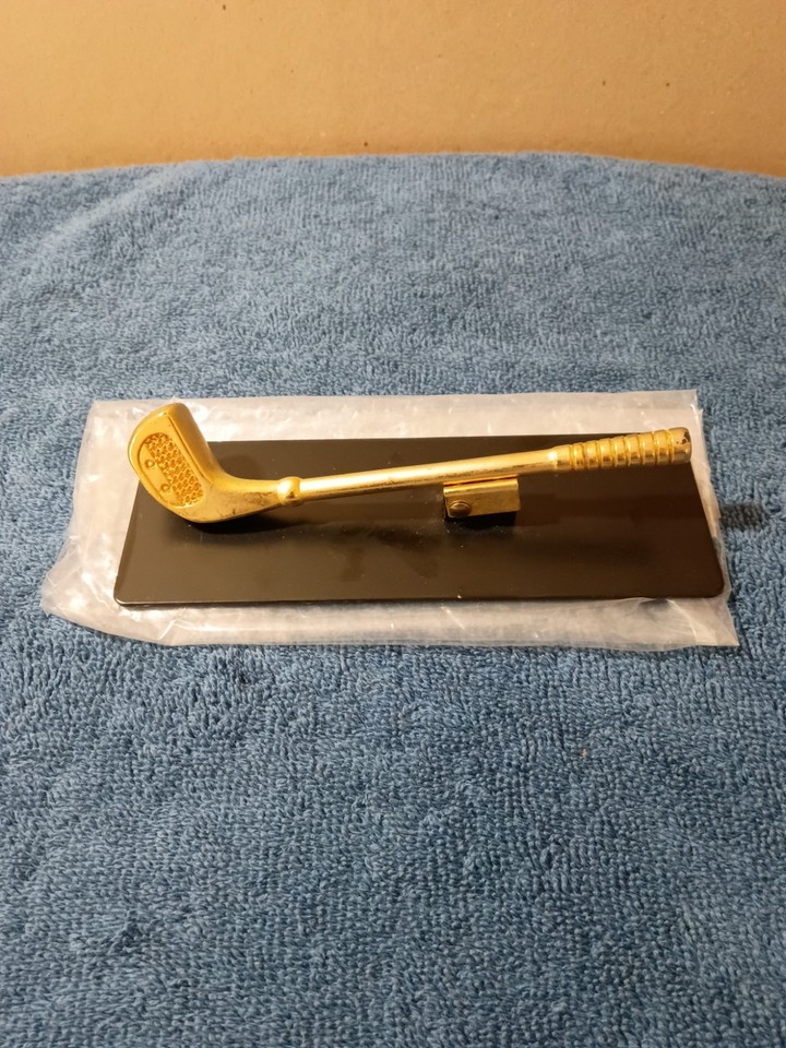 A miniature brass golf club that doubles as a paper clamp — the kind of punny executive desk toy that feels equally at home in a corner office or a thrift-store lover's collection.