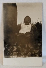 Postcard RPPC Smiling Baby with Bib Sitting In Chair early 1900s A23