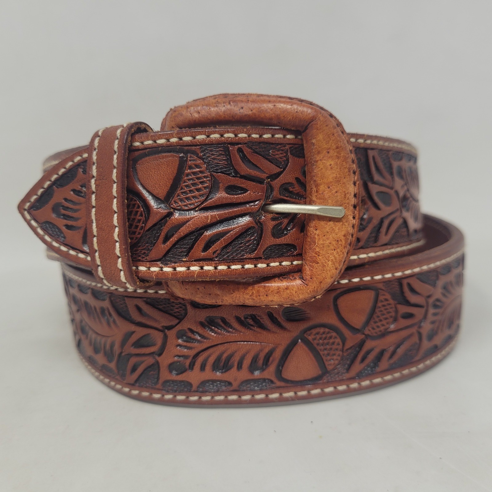 Brown Vogt Silversmiths hand-tooled leather belt with an acorn pattern.