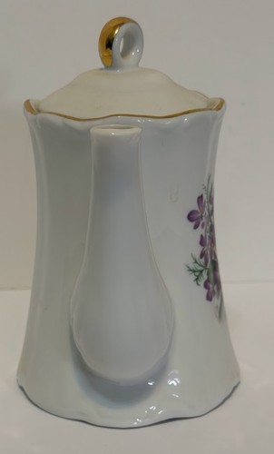 White porcelain teapot with gold rim, lid, and handle; floral sprig of purple and green leaves on the side.