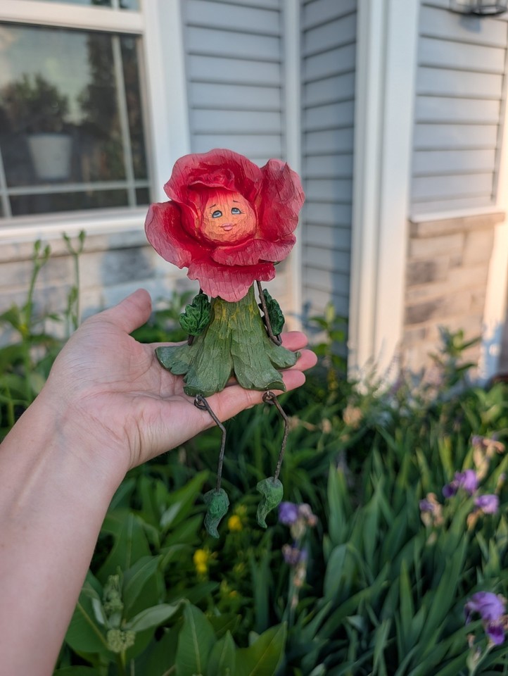 A jointed, smiling anthropomorphic rose flower shelf sitter — the kind of delightfully weird decorative piece that stops guests in their tracks.