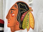 Vintage white Chicago Blackhawks hockey sweatshirt with black and orange head logo and green leaf accents on black jersey.
