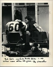 Press Photo Bob Golic comforts Bubba Baker in the locker room after the game.