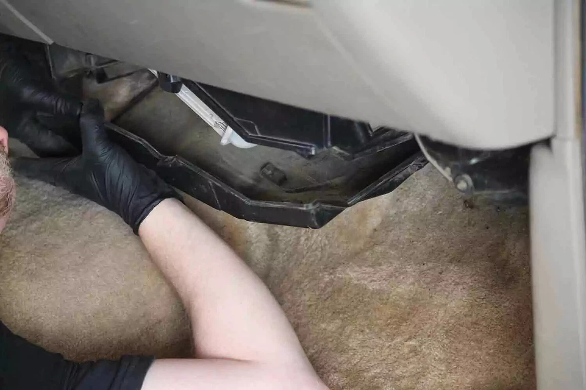 A mechanic wearing a black glove removes the cover of the HVAC unit.