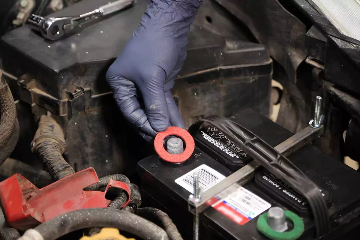 Car battery with red and green felt washers being installed.