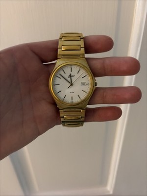Vintage gold-tone wristwatch featuring a clean white dial with slim hour markers
