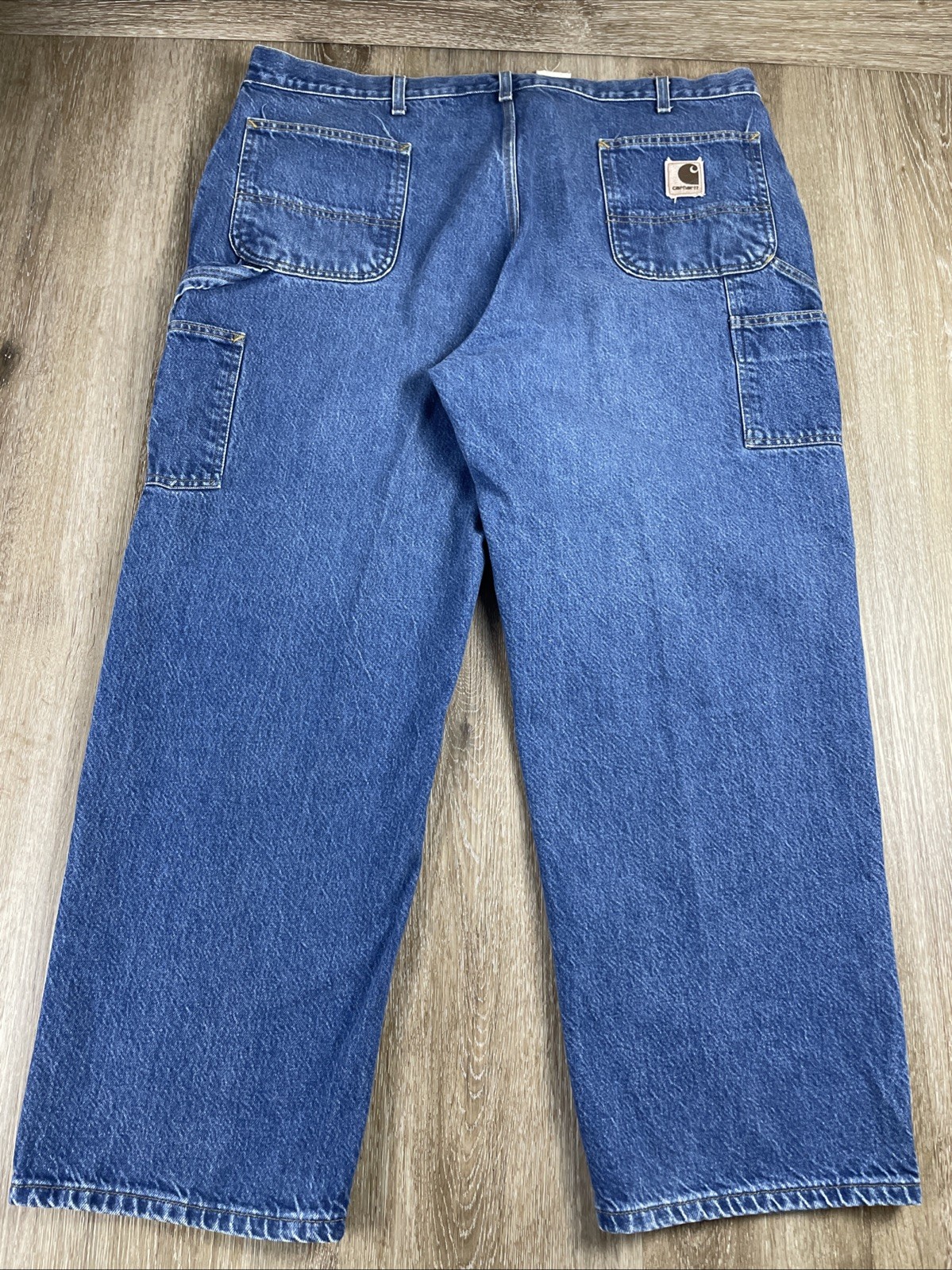 Blue denim Y2K Carhartt men’s carpenter jeans with faded thighs, two front pockets, and visible Carhartt logo on waistband.