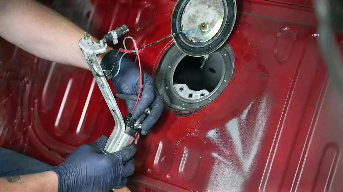  A mechanic wearing nitrile gloves connects the electrical lead to the new fuel pump.