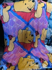 A vintage Disney Tigger comforter with a colorful striped background.