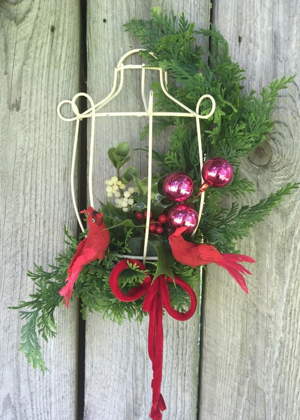Vintage handmade Christmas decor with cardinals, pine, holly, and berries in bird cage