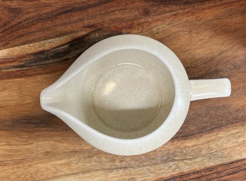 Light gray ceramic coffee mug with white handle, tan interior, and subtle speckled beige K9 logo on wooden surface.
