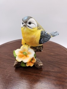 Goldfinch Bird Figurine sitting on a branch with flowers. 4.5 X 4.5". Pre-owned