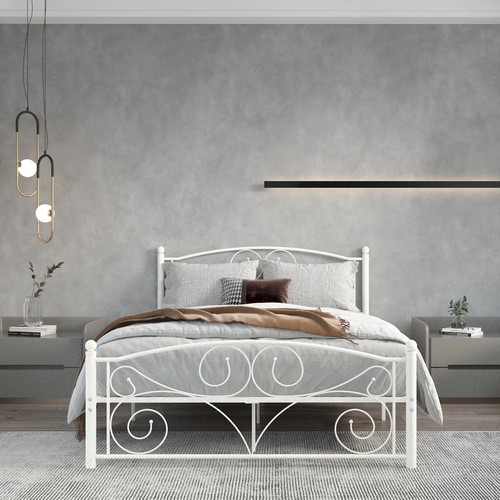 White metal bed frame with unique floral scrollwork headboard and footboard, placed in a light gray bedroom with bedside tables.