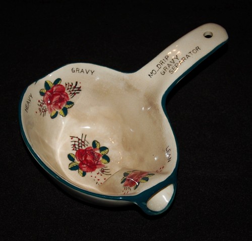 White ceramic gravy separator with red and teal floral pattern, labeled “Heavy,” “Lean,” and “No-Drip” on dark background.