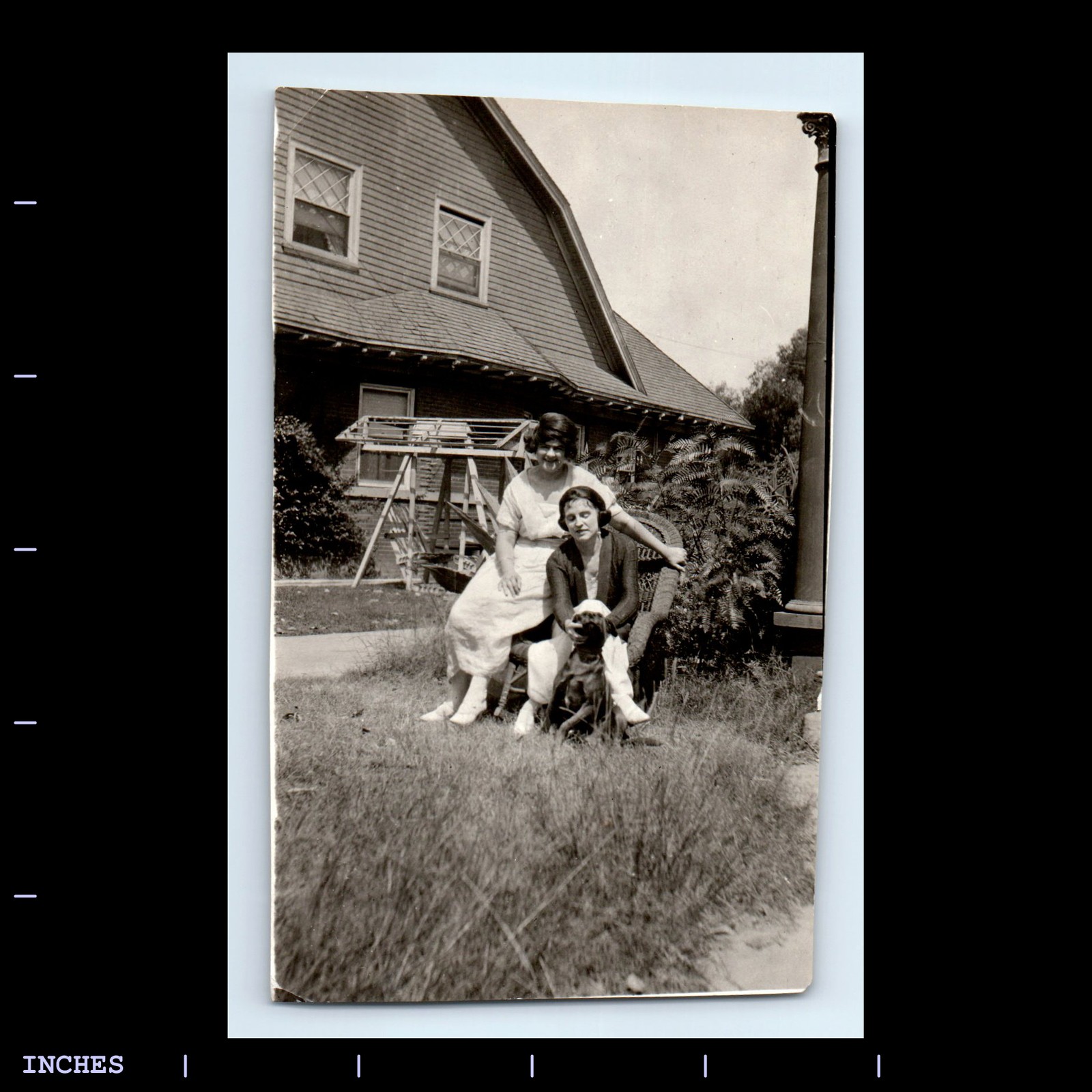 Vintage black and white photo of women with dog sitting outside a house
