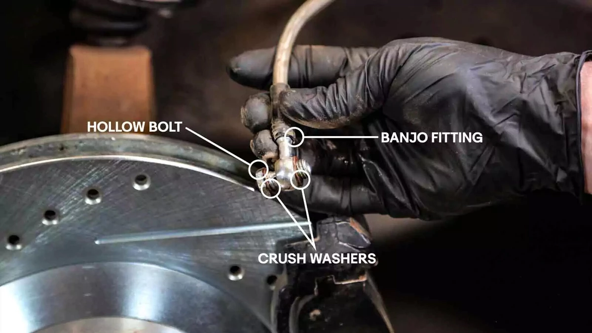 A mechanic examining a brake line and fitting.