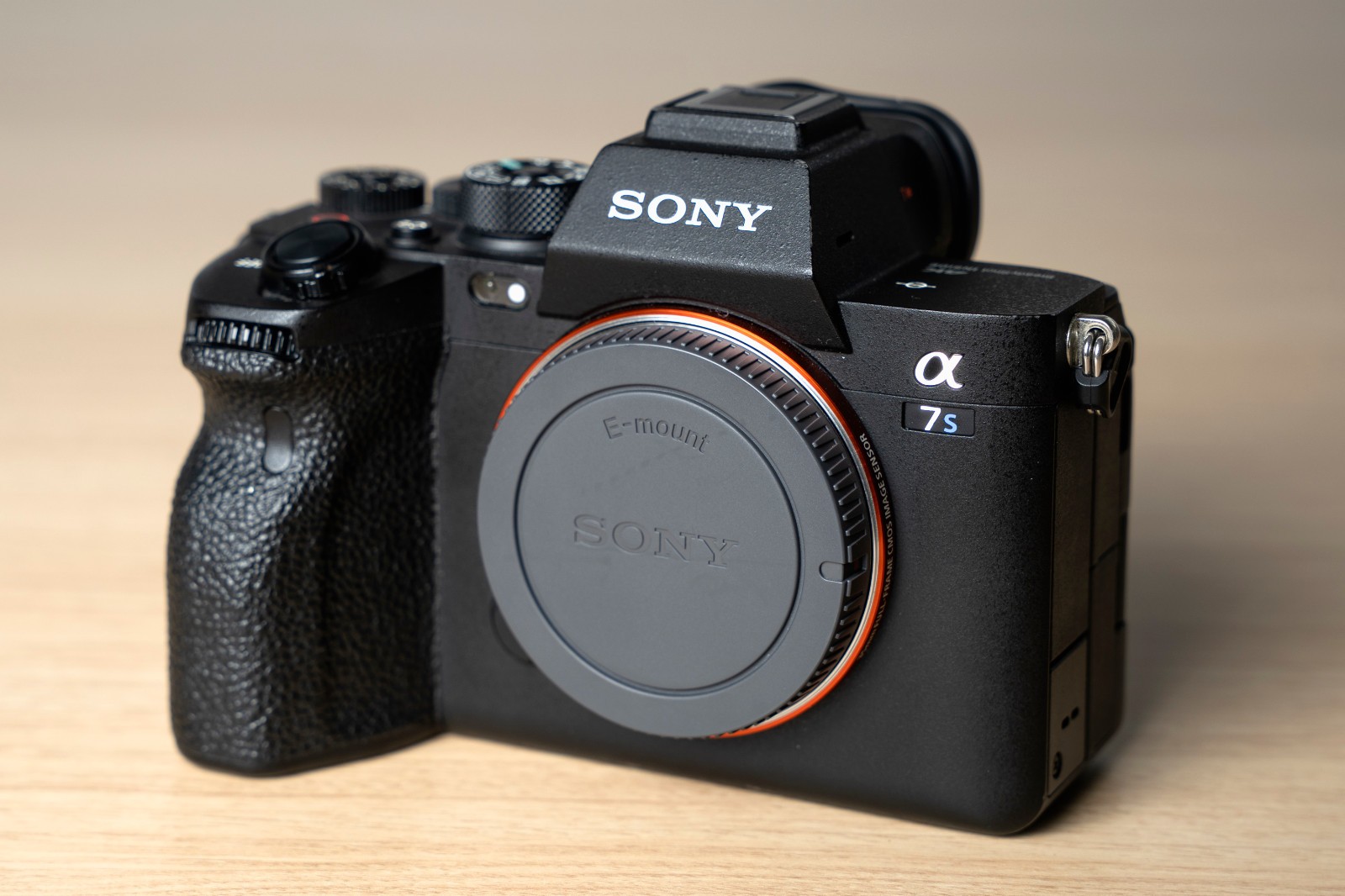 Black Sony Alpha a7S III body with silver accents, front screen, and two black batteries on a wooden surface.