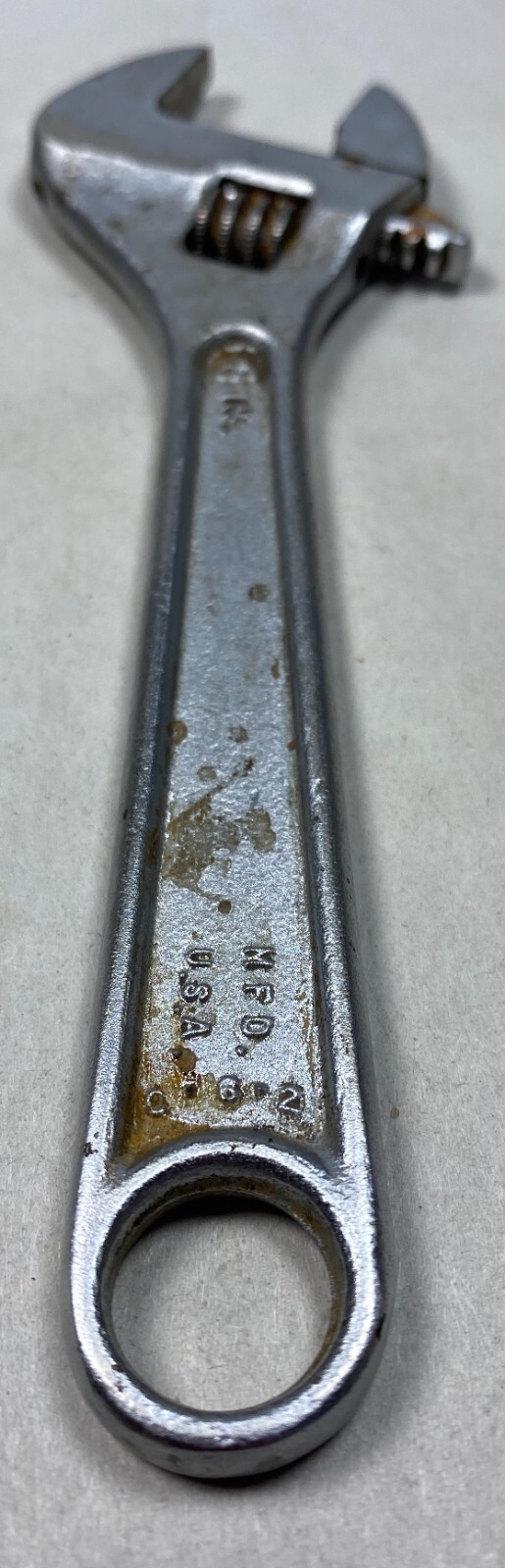 Silver 6-inch adjustable crescent wrench with worn handle, yellow “MFD. IN U.S.A.” text, and two metal screw heads.