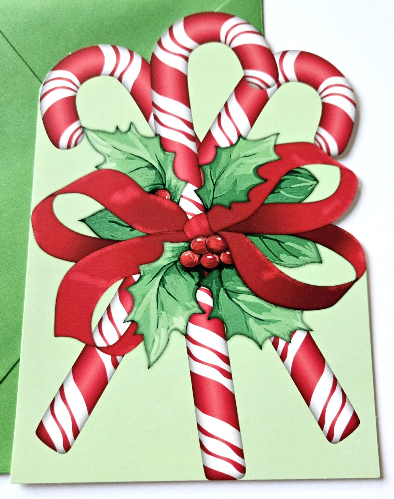 Bastones de caramelo para tarjeta de Navidad envueltos con lazo y bayas de acebo Sweet Moments