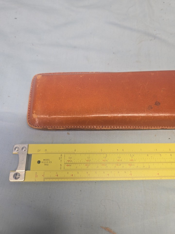 A USA-made Pickett 1010 ES slide rule in its original leather case — the pre-calculator engineer's weapon of choice, still fully usable and deeply satisfying to hold.