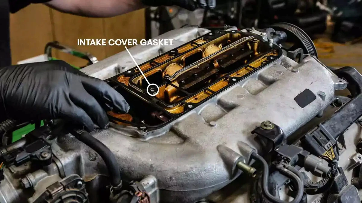 A mechanic removes a stamped steel intake cover gasket.