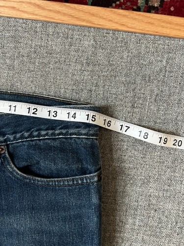 Dark wash VTG 1990s Levi’s Superlow 518 bootcut jeans, waist 31, on hanger with measuring tape.