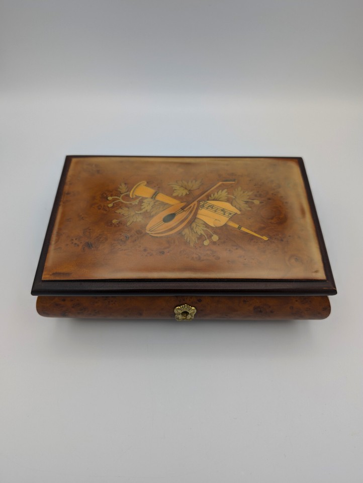 A footed Reuge wooden keepsake box — Reuge is the Swiss watchmaker of music boxes, so even a small piece carries serious pedigree and mechanical soul.