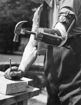 Captain Maxwell uses his artificial arm to hammer in a nail. - 1942 Old Photo 1