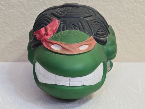 Green Teenage Mutant Ninja Turtles football Raphael with white mask, red bandana, and orange eye lenses on a textured front.