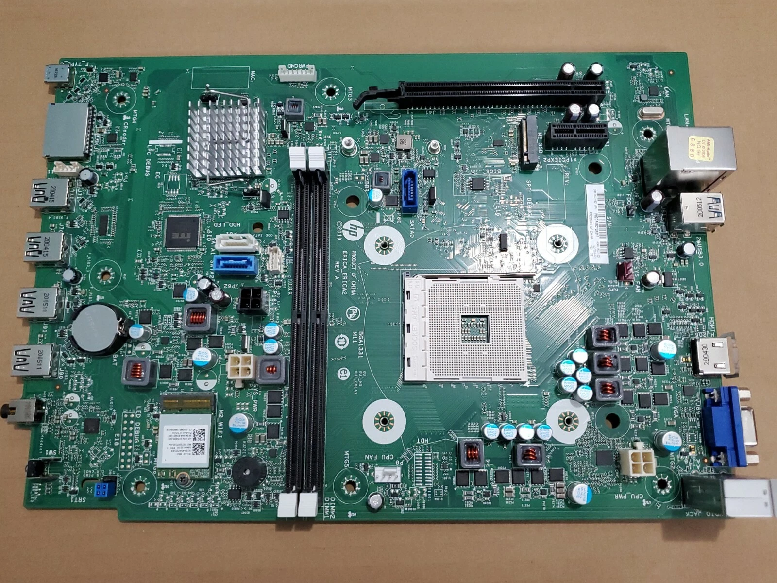 Green HP Pavilion TG01 motherboard with AM4 CPU socket, black PCIe slot, USB ports, and silver heatsinks on surface.