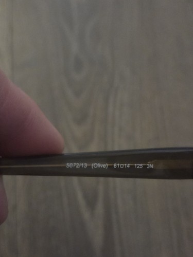 Close-up of black Coach HC 8053 sunglasses lens with brown tint, white frame, and gold “S072/13” text on right lens.