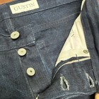 Front pockets, button closure, and white “Gustin” label inside waistband of blue denim jeans.