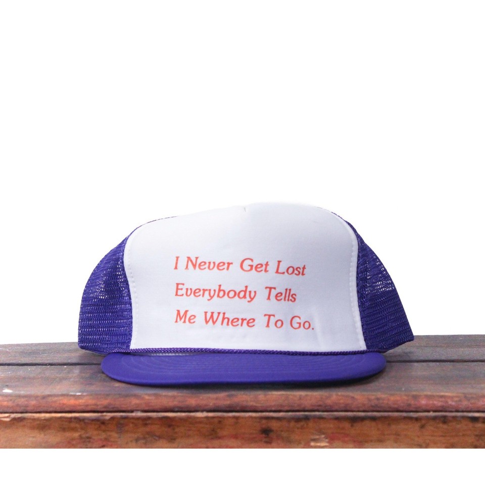 A pre-owned vintage purple trucker hat with 'I Never Get Lost' — the kind of deadpan dad humor that looks genuinely cool worn ironically.