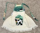 White vintage cotton kitchen towel with green cow and tree applique, red farmhouse VTG label, and blue fringe trim.