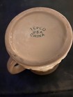 Beige ceramic mug with white text reading “TEPCO U.S.A. CHINA” on a dark background.