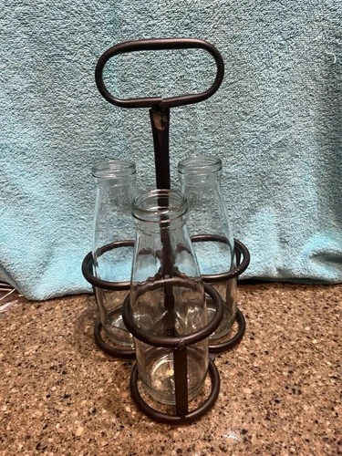 Vintage-style metal milk bottle caddy with three glass bottles.