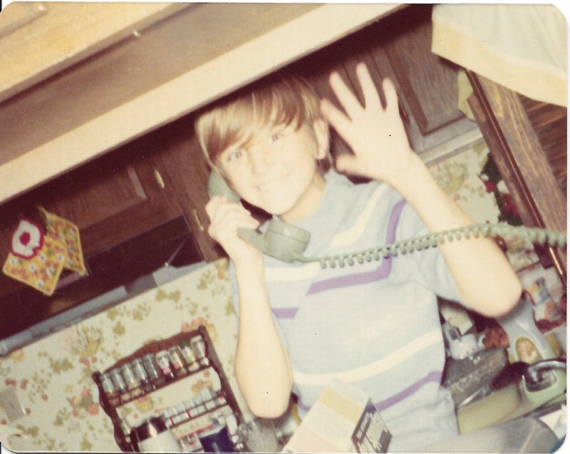 vintage color photo boy talking on the telephone waving hand in kitchen