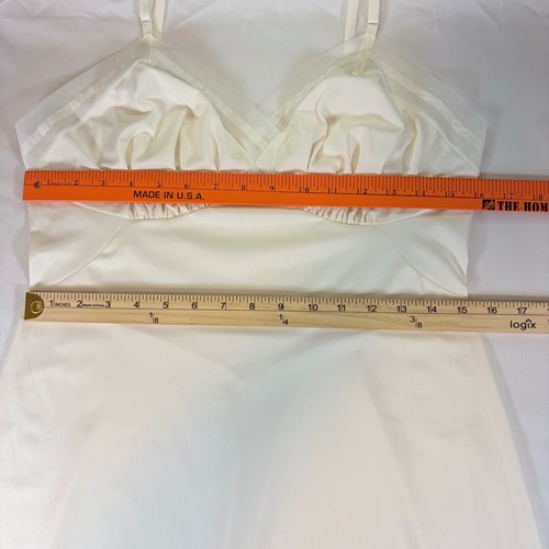 White nylon full slip with sheer mesh trim, fitted bodice, and long sheer skirt, displayed flat with orange ruler.