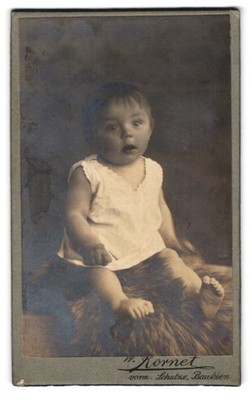 Fotografie W. Kornet, Bautzen, Süßes Kleinkind im Hemd sitzt auf Fell 