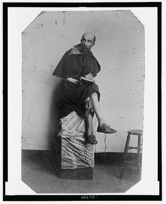 Full-length of man dressed as a monk,on a cloth-covered crate,1860-1900