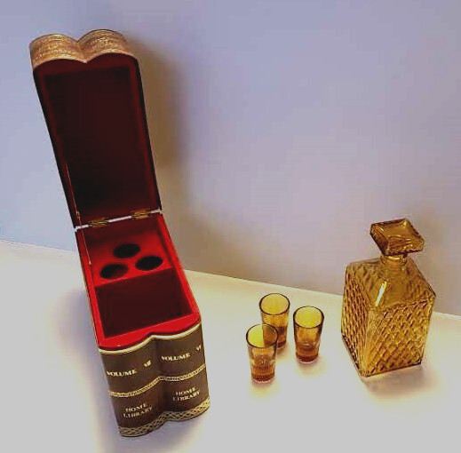 A secret-book decanter disguised as leather-bound volumes VII & VI with amber glass and 3 hidden shot glasses — peak clandestine home-bar energy.