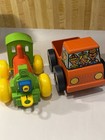 Green vintage Tupperware toys: red/blue steam engine and orange truck with yellow wheels, made in the USA.