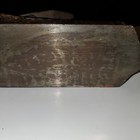 Worn smooth bottom of a blackhawk C557MP wood hand plane with visible scratches and textured surface.