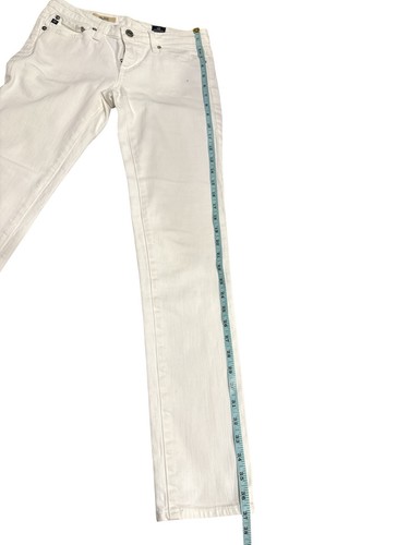 White AG Adriano Goldschmied jeans 25R with five-pocket design, shown on left leg with measuring tape along length.