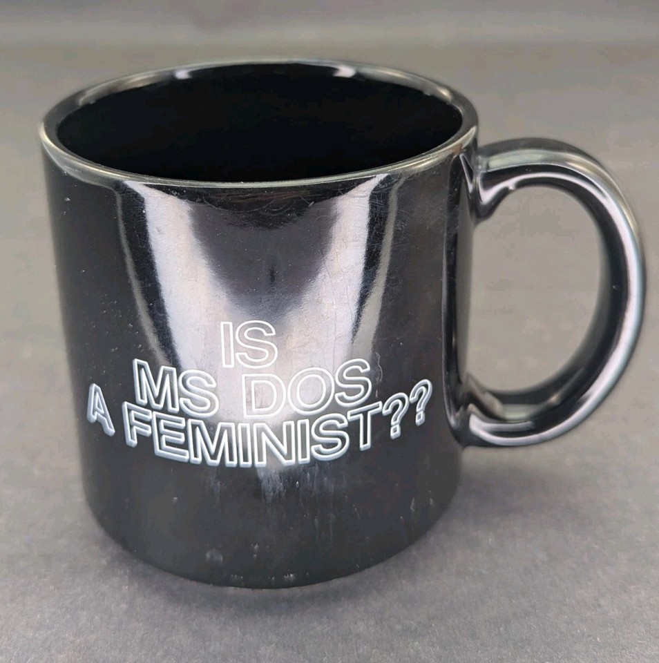 A vintage mug asking 'Is MS-DOS a Feminist?' — a genuinely period-correct artifact of 80s/90s tech culture that works as both a conversation piece and a usable daily mug.