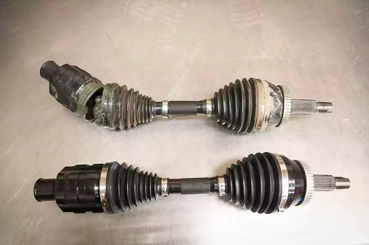 Two CV joints, displayed on a white background, one old, one new. The CV joint at the top is broken and cannot be repaired.